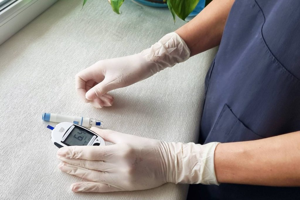 Hoitaja katsoo lukemaa verensokerimittarista.